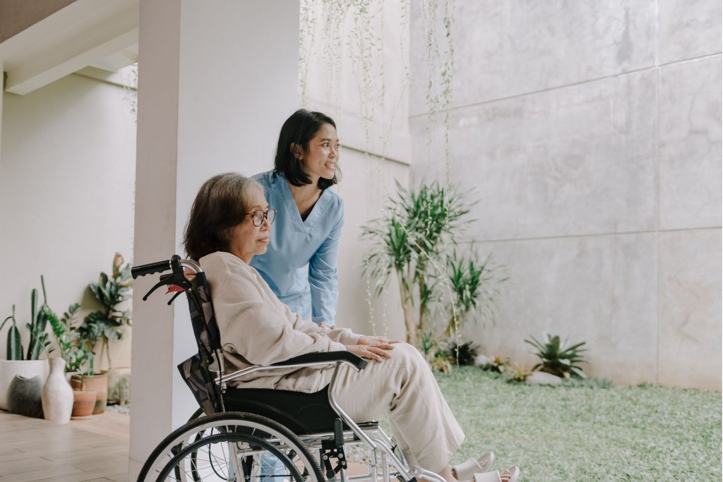 A young travel nurse helping a patient in a wheelchair
