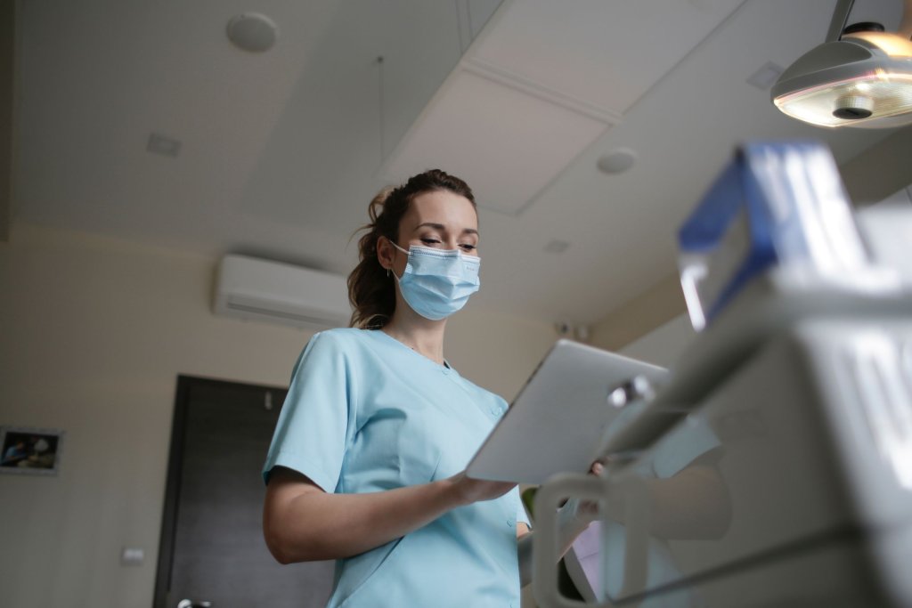 A nurse wearing a mask and viewing something on an iPad