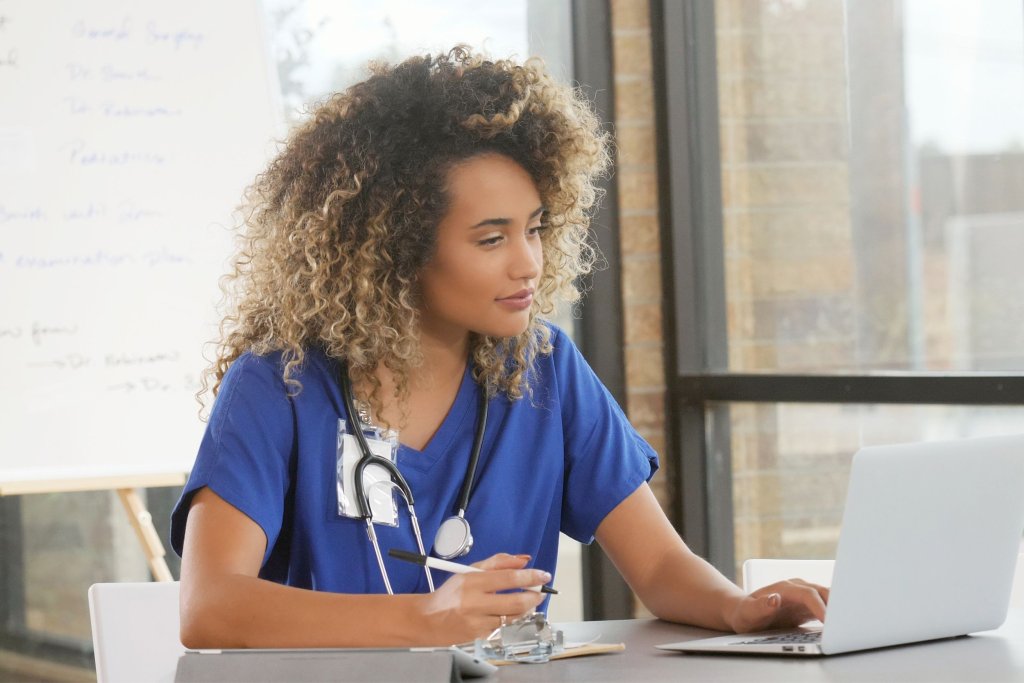A nurse writing notes and working on her computer