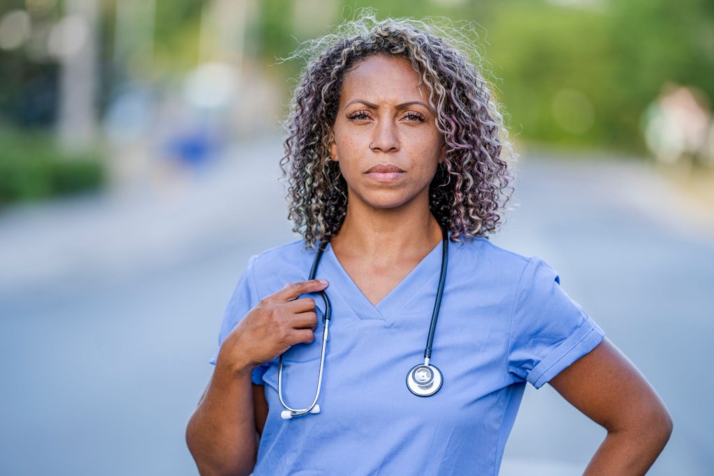 A nurse in scrubs holding a stethoscope