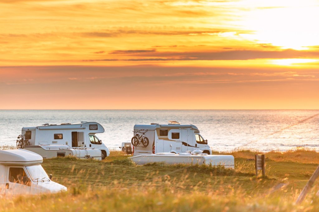 RVs parked by a body of water at sunset