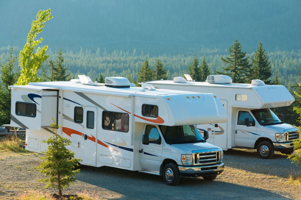 Two RVs parked next to each other near a bunch of trees